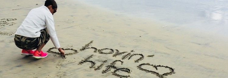 Ebony writing it the sand on the beach