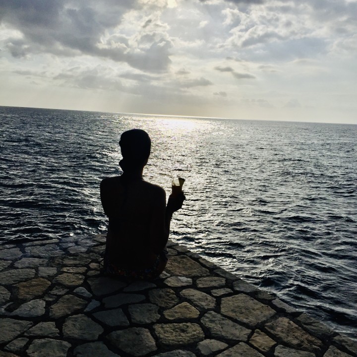 Ebony watching the sunset near the ocean.