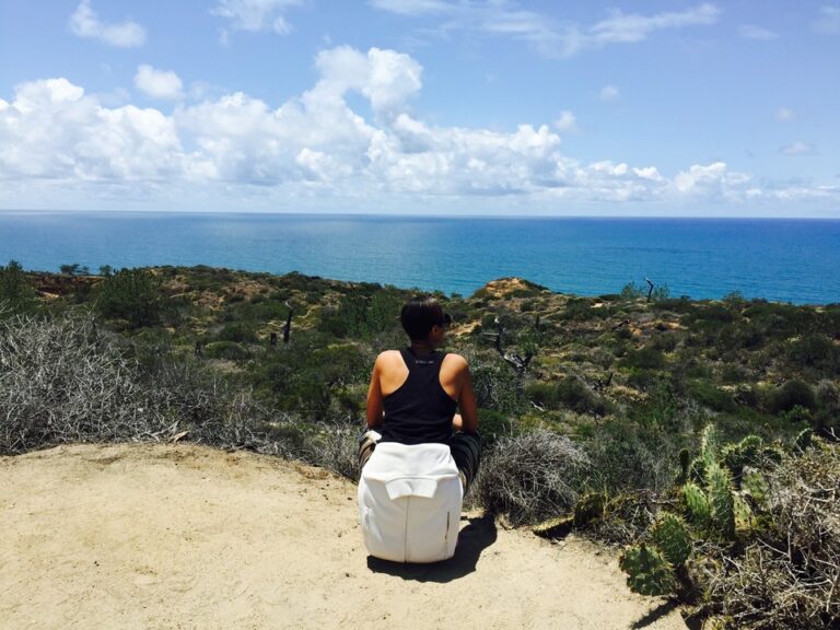 person sitting coast side looking at the ocean